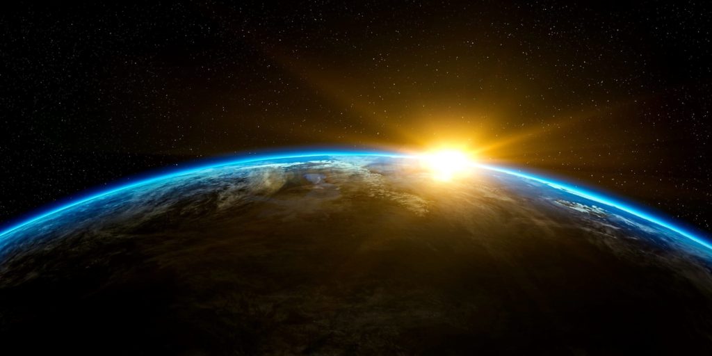 O planeta Terra visto do espaço com um sol nascendo por trás dele. Em constrate e metáfora ao texto.