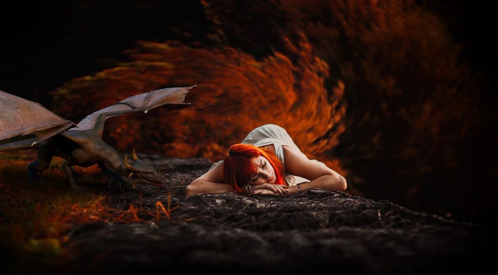 Uma jovem moça ruiva deitada no chão dormindo, ao seu lado direito um pequeno dragão. 