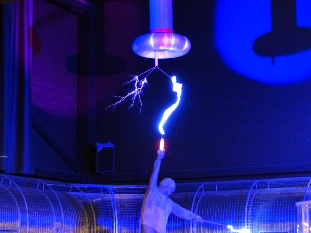 Apresentação onde homem manipula a energia elétrica em um experimento assistido.